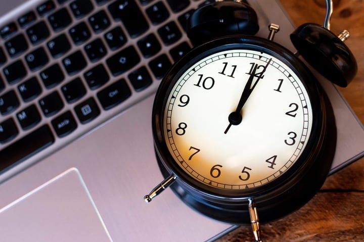 A ticking alarm clock on a laptop keyboard, representing high MTTR and IT incident resolution time.