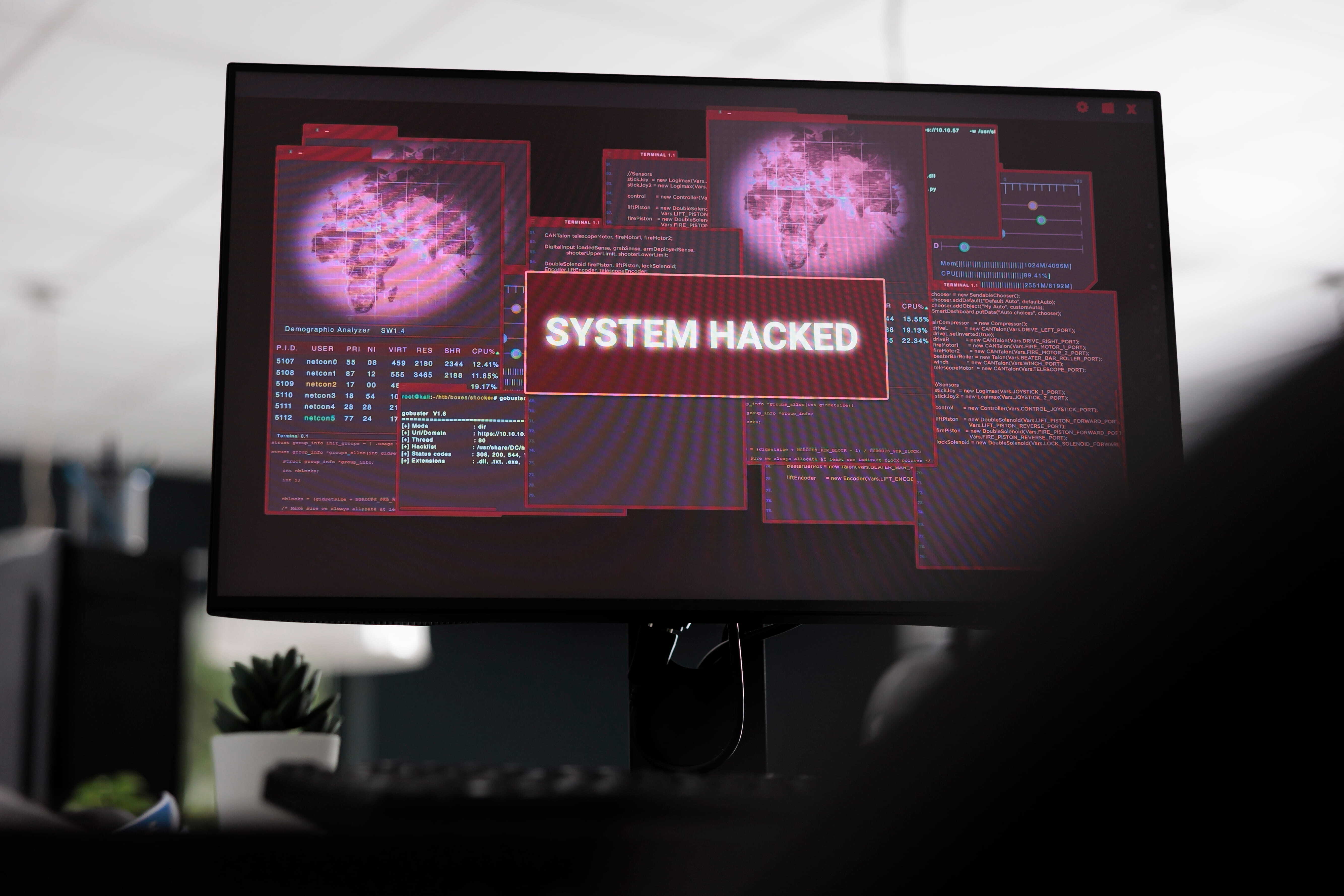 A computer screen displaying a “system hacked” warning with multiple data panels, representing the risk of a data breach.