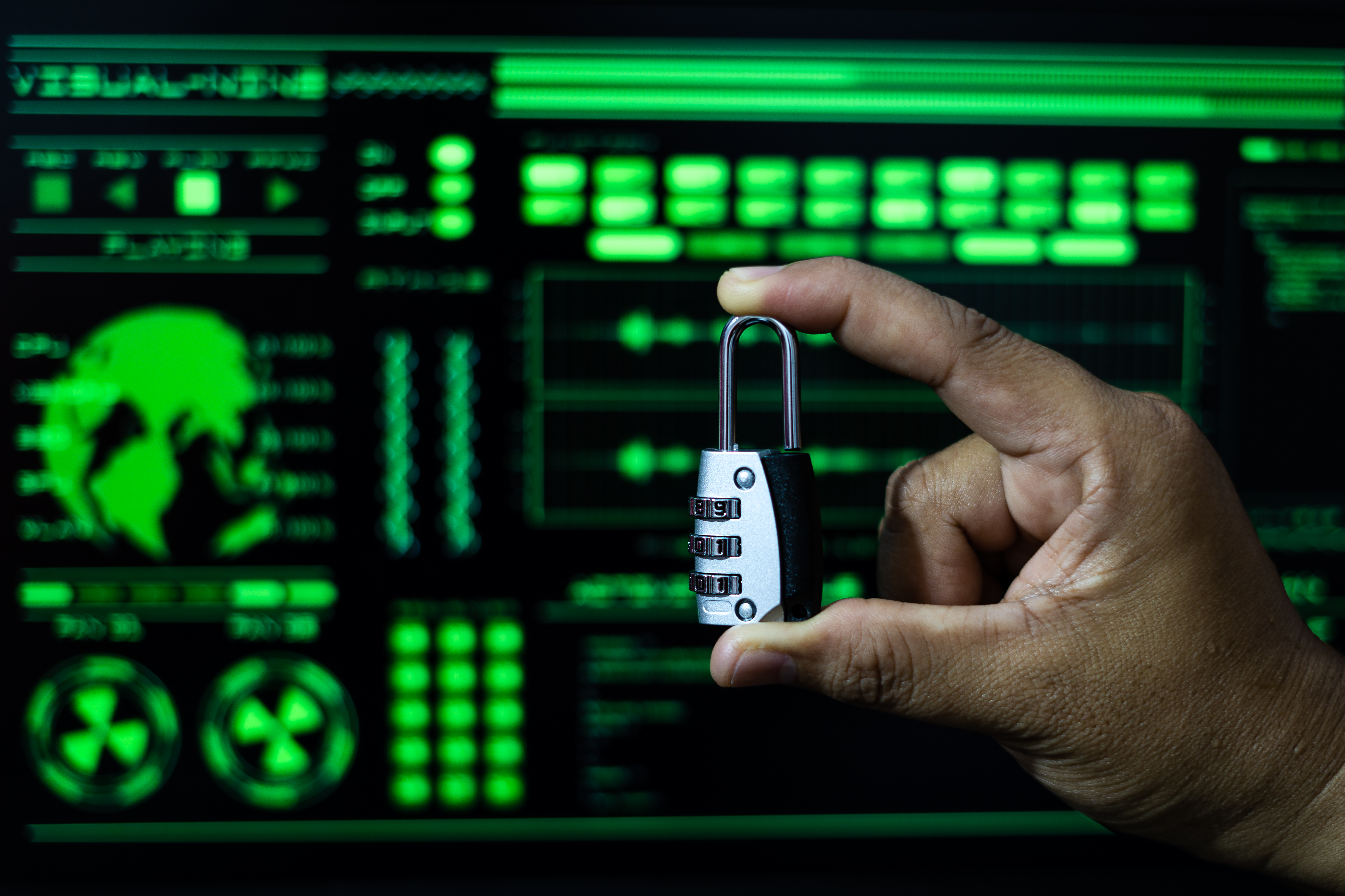 A hand holding a padlock in front of a digital security dashboard, showing how to prevent cyber security attacks.