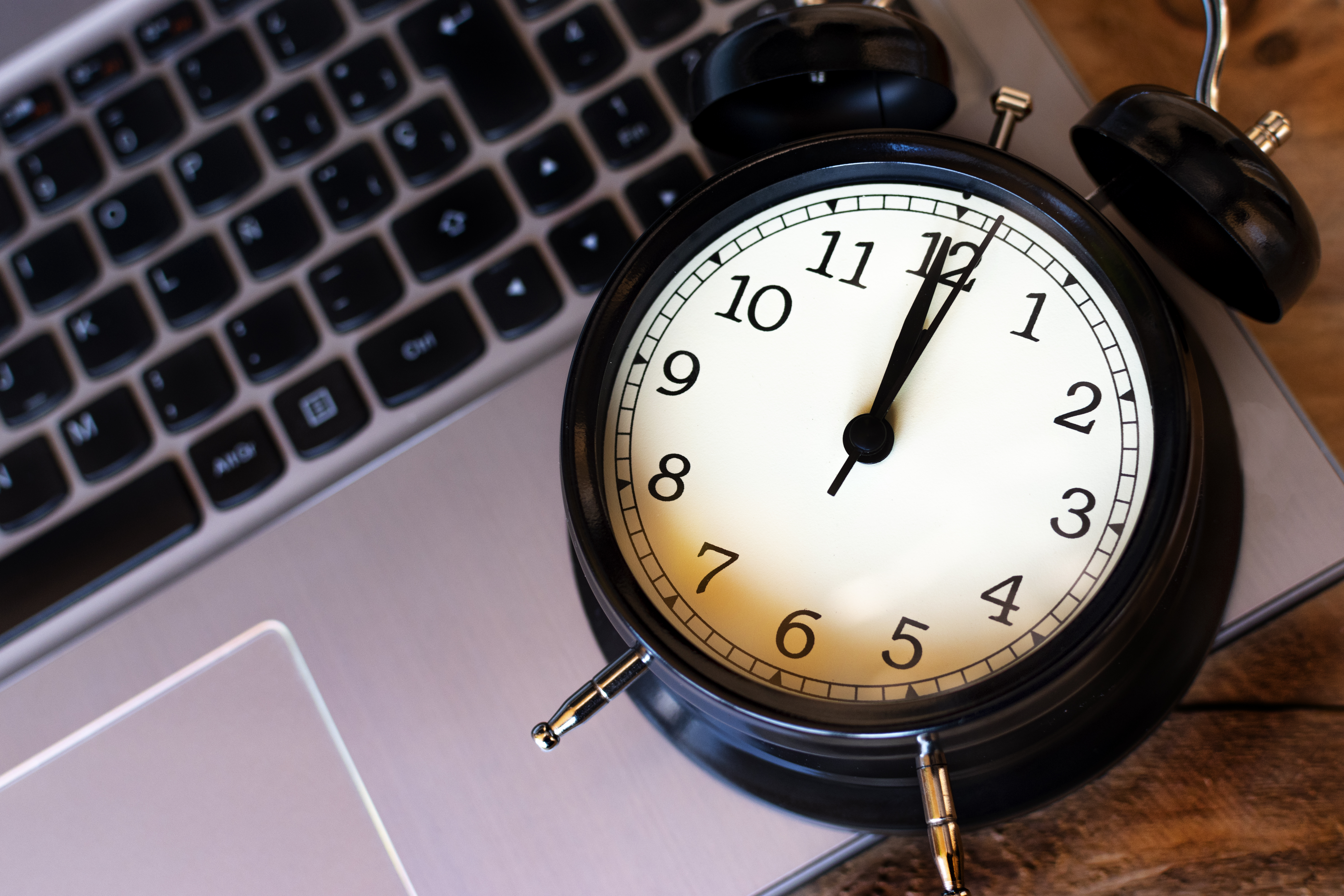 A ticking alarm clock on a laptop keyboard, representing high MTTR and IT incident resolution time.